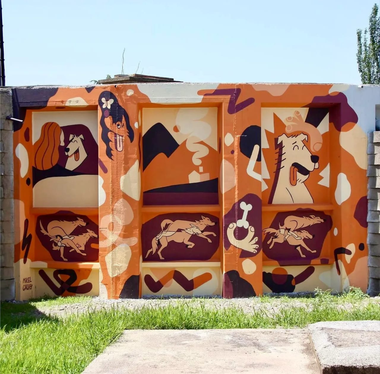 Mural con motivos de perros y montañas en colores naranjas, marrones y blancos.