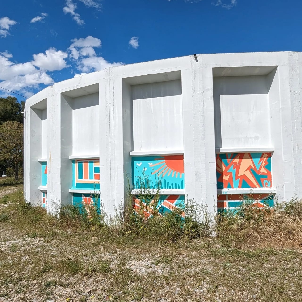 Muro blanco con secciones de colores bajo un cielo azul.