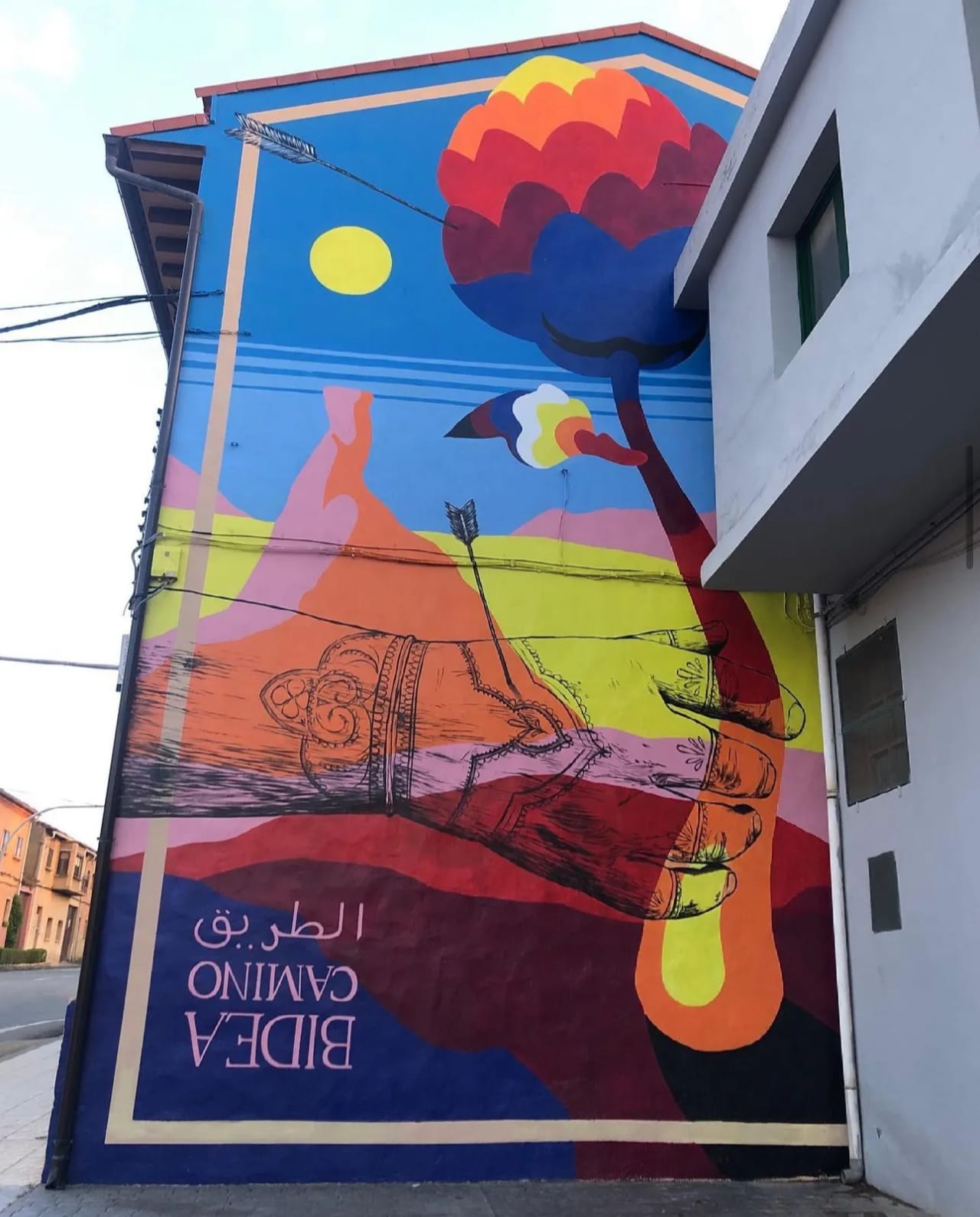 Mural colorido en la pared de un edificio con un hombre volando con un globo aerostático.