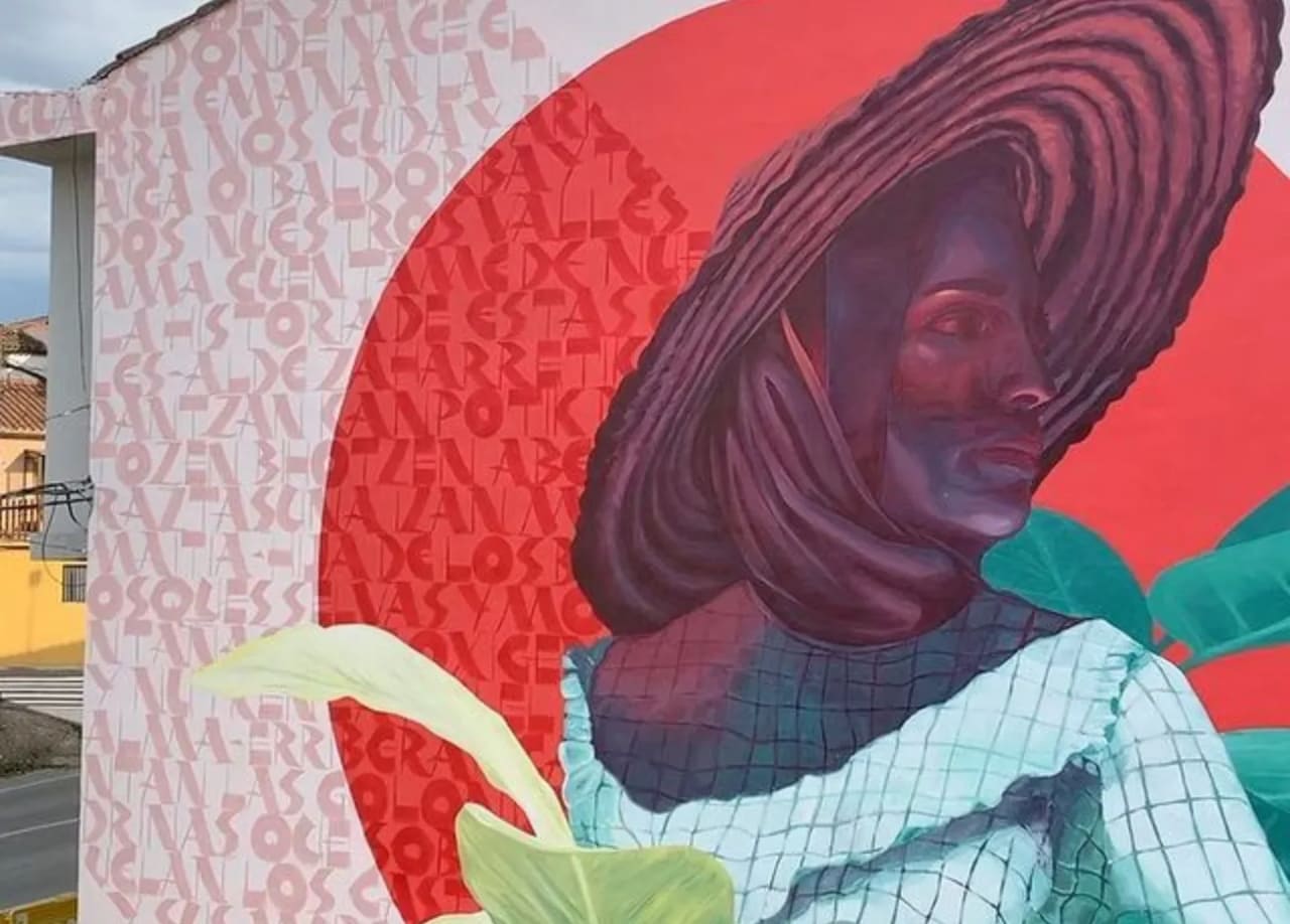 Mural de una mujer con sombrero y flores en un entorno urbano.