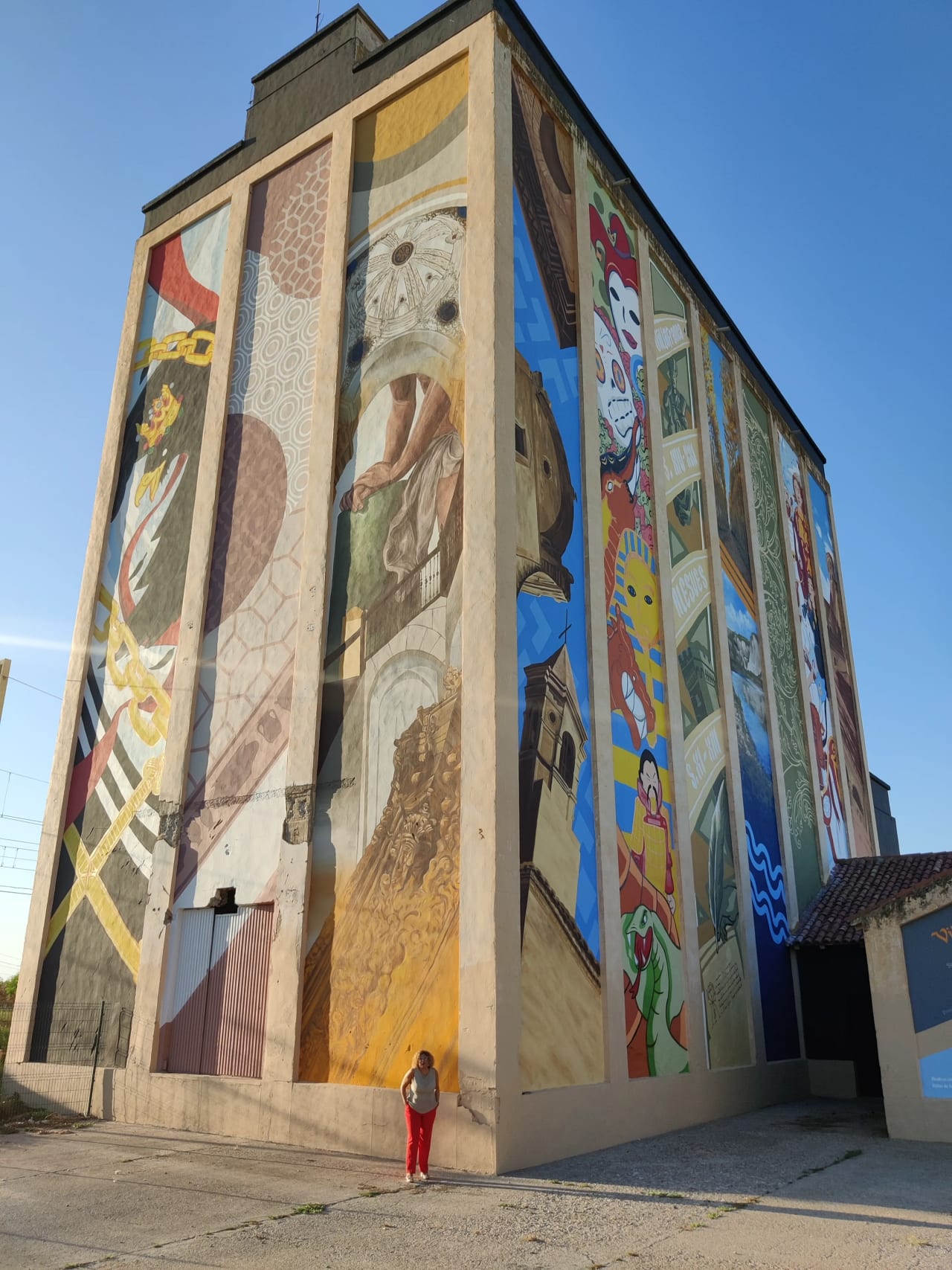 Mural en un edificio con una mujer parada al frente.