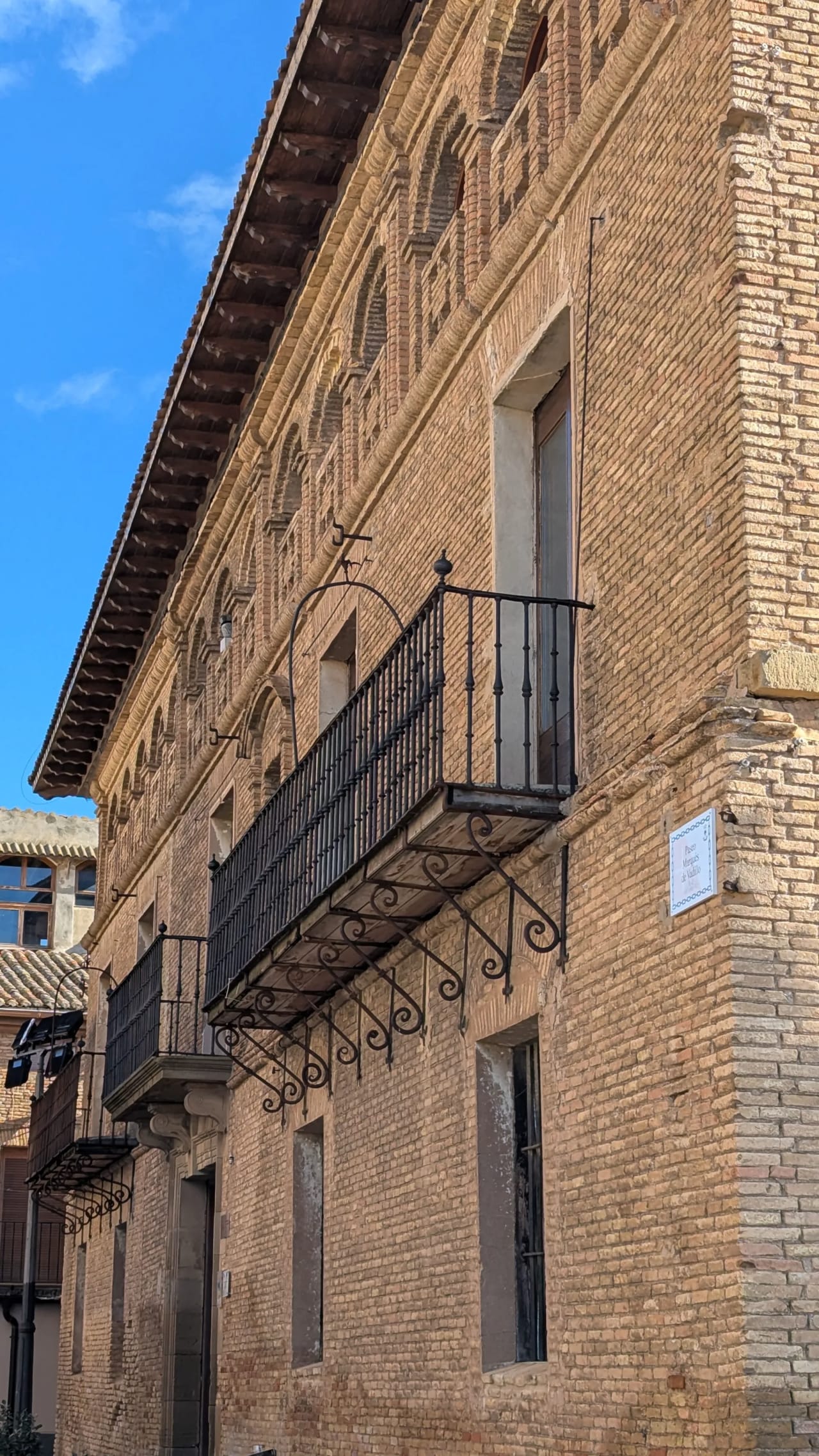 Fachada de ladrillo con balcón de hierro forjado.