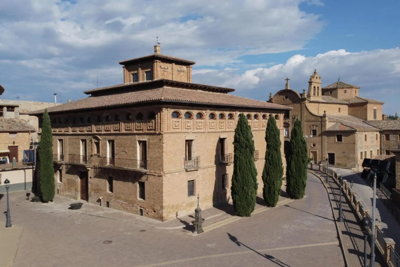 Edificio histórico con torre, estilo arquitectónico antiguo, en una plaza tranquila.