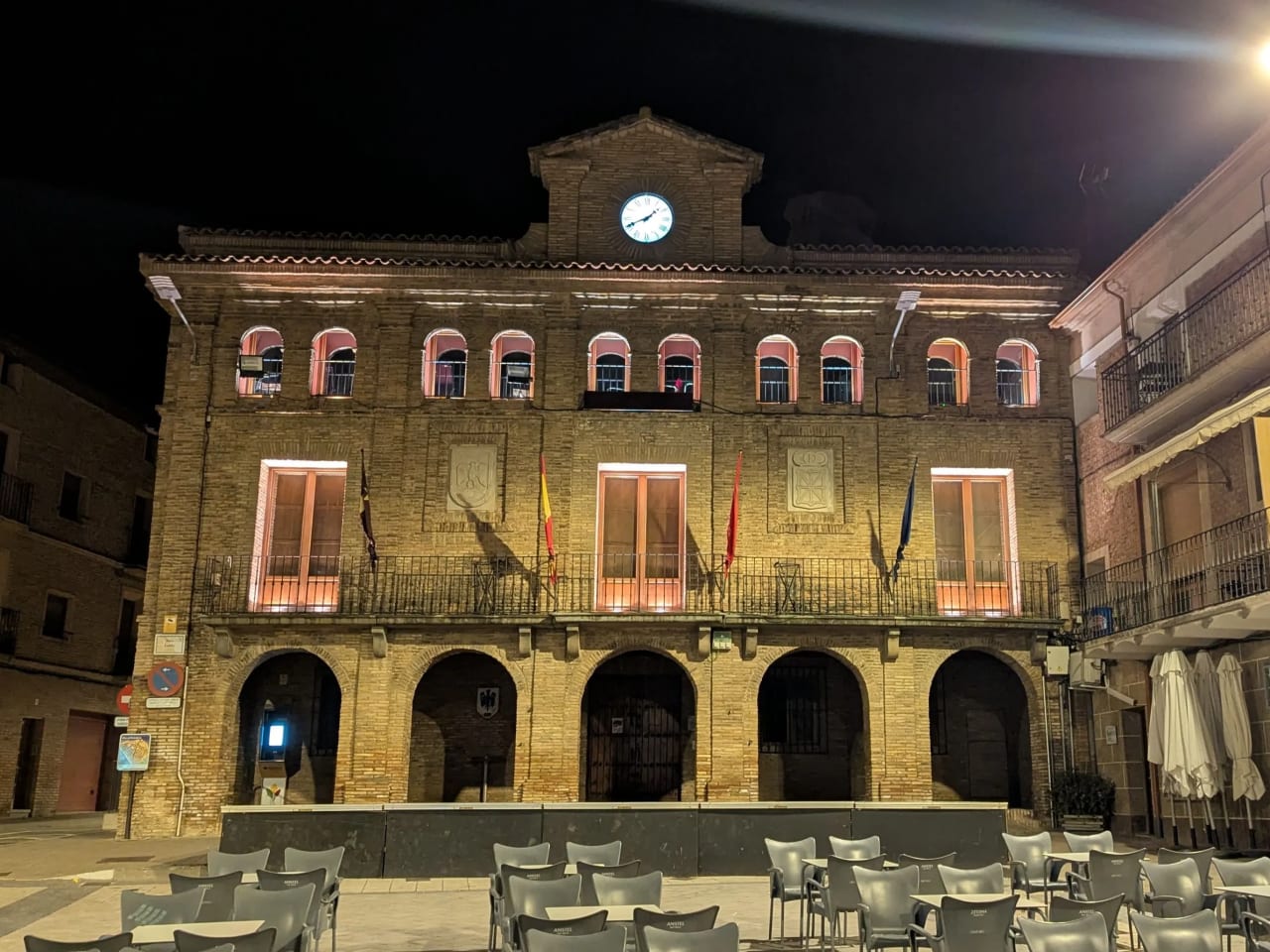 Ayuntamiento iluminado por la noche en un entorno tranquilo.