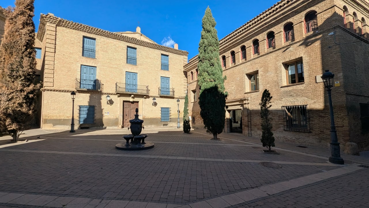 Un claustro o patio interior con fuente en el centro, rodeado de edificios históricos de ladrillo.