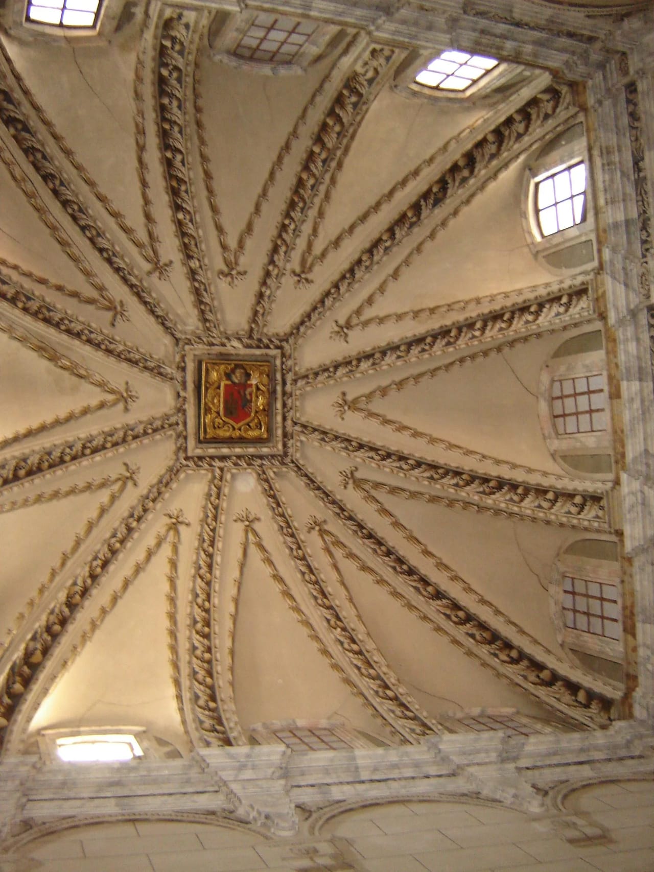 Techo decorado con arcos y un escudo en el centro.
