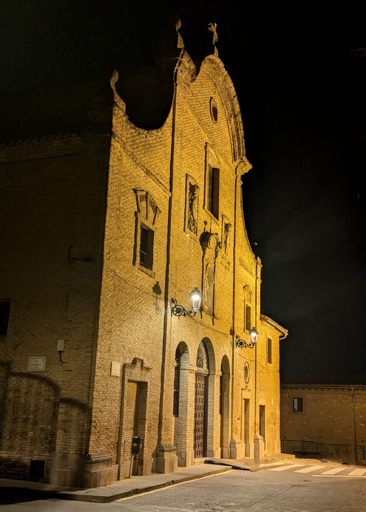 Iglesia iluminada en la noche con fachada de ladrillo y detalles arquitectónicos.
