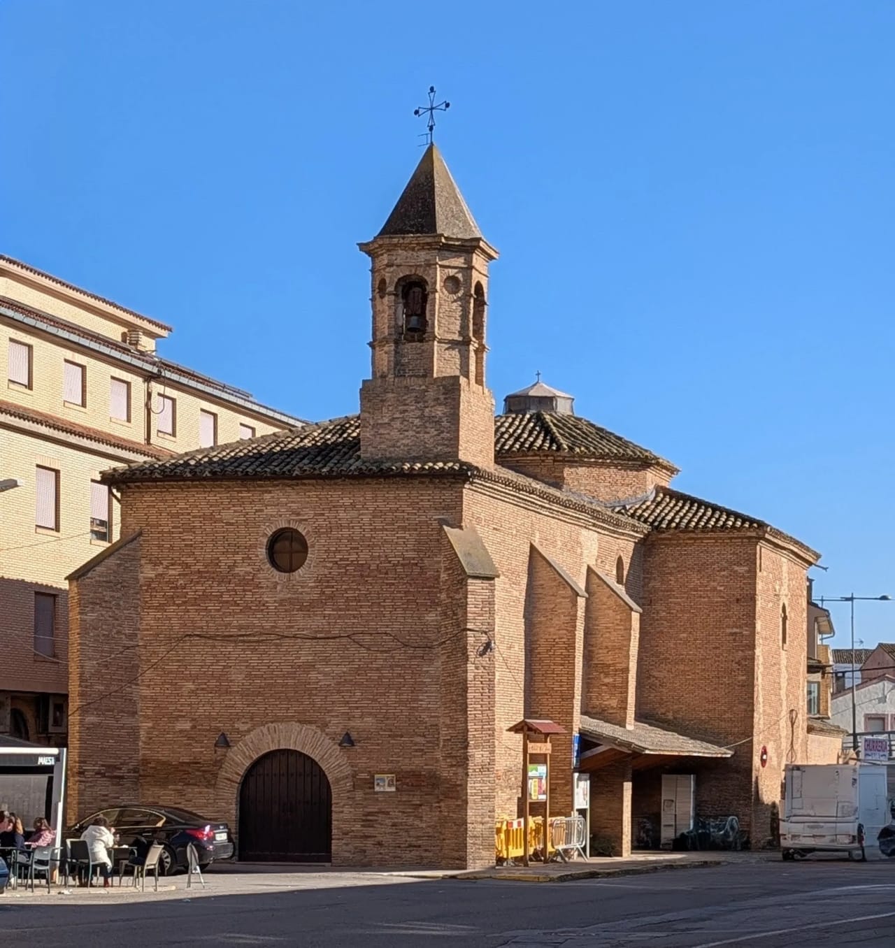 Iglesia de ladrillo con torre campanario y cúpula bajo cielo azul.