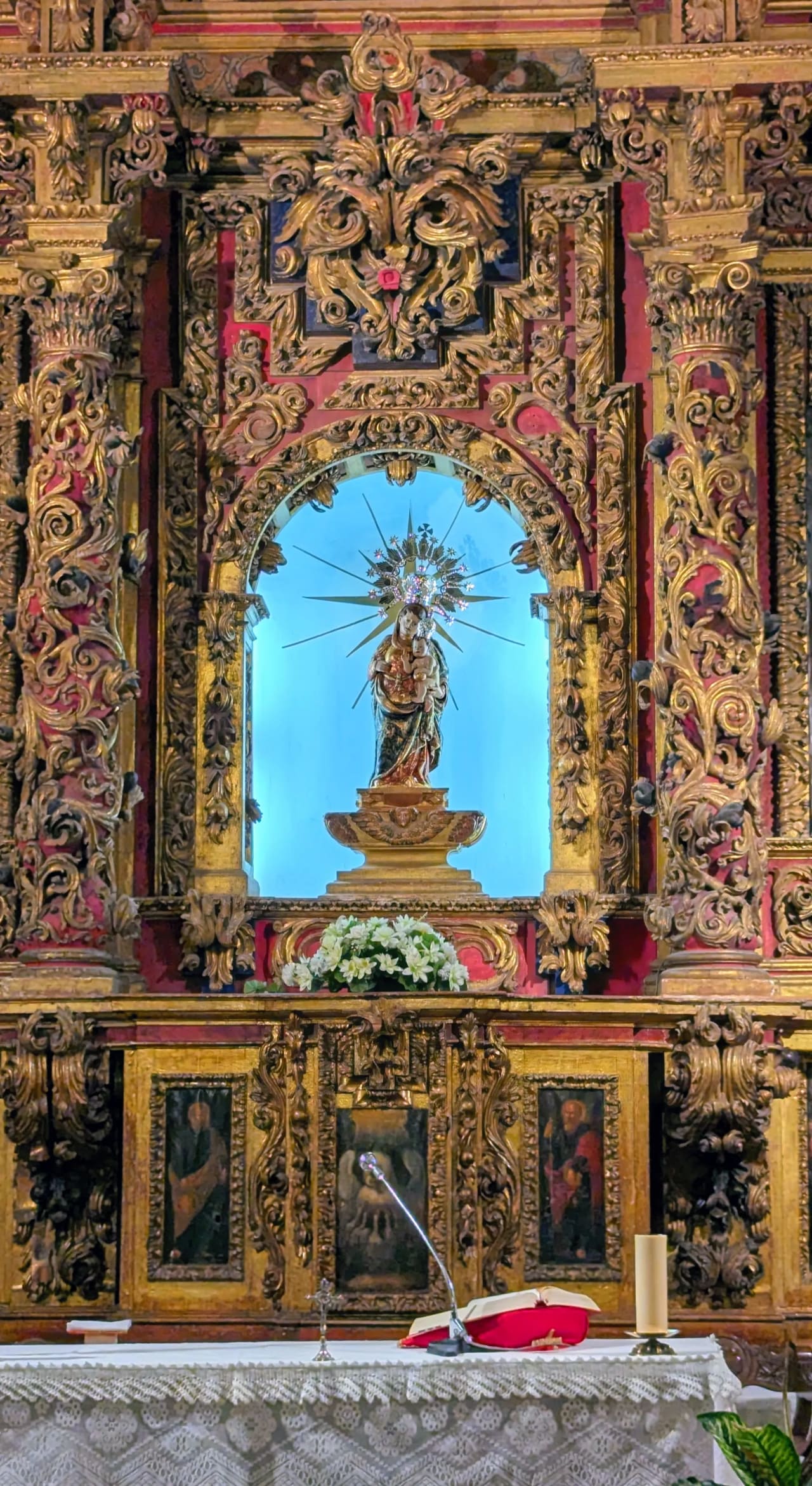 Estatua de la Virgen María con el niño Jesús en ornamental altar barroco.