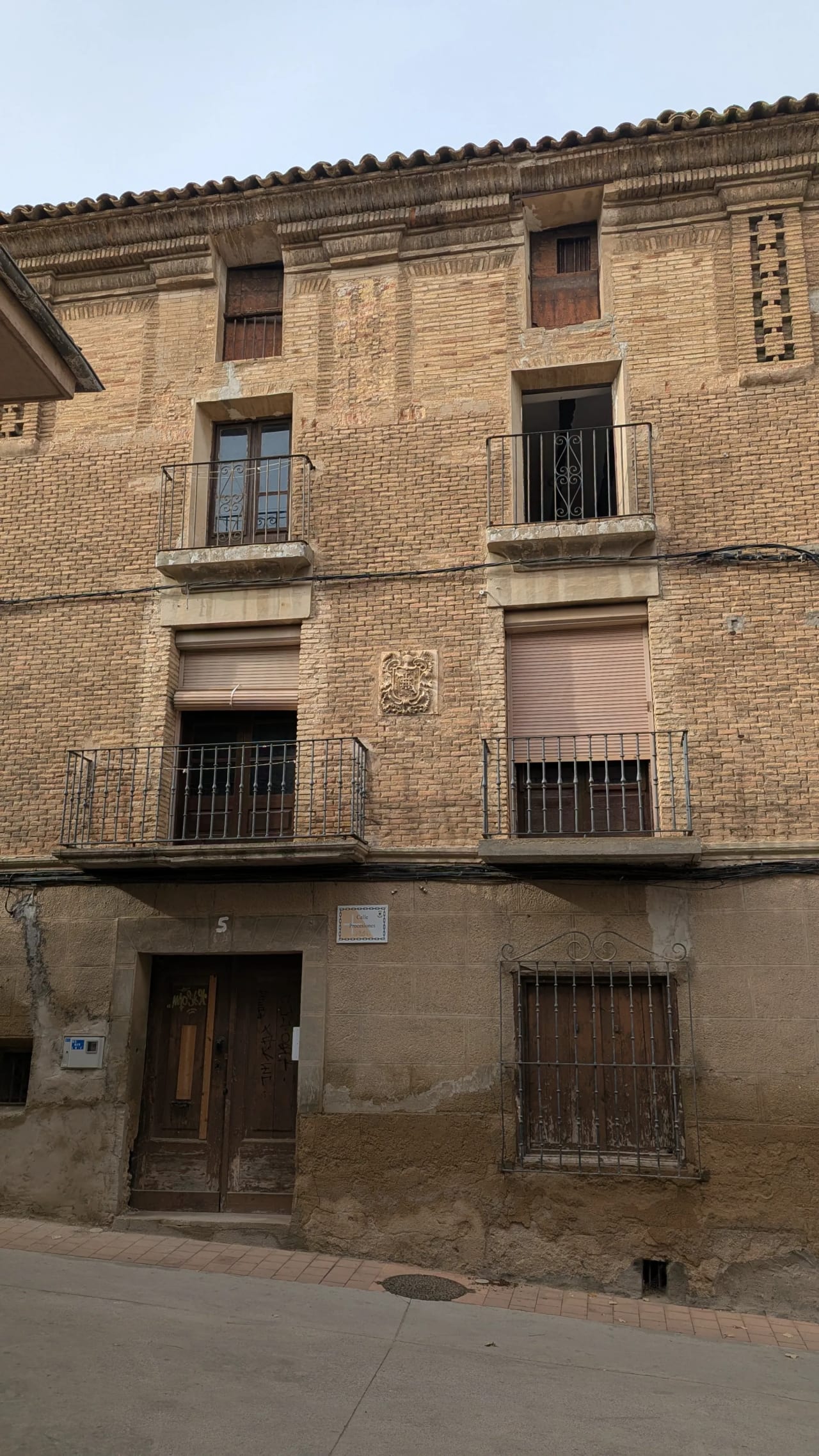 Edificio antiguo de ladrillo con balcones y barandillas de hierro.