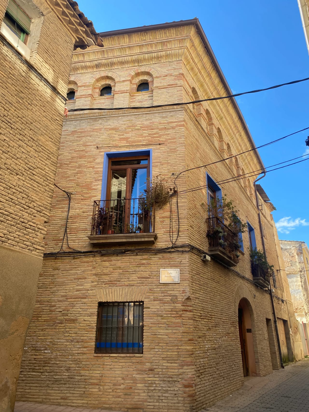 Edificio de ladrillo con balcones y ventanas en una calle estrecha.