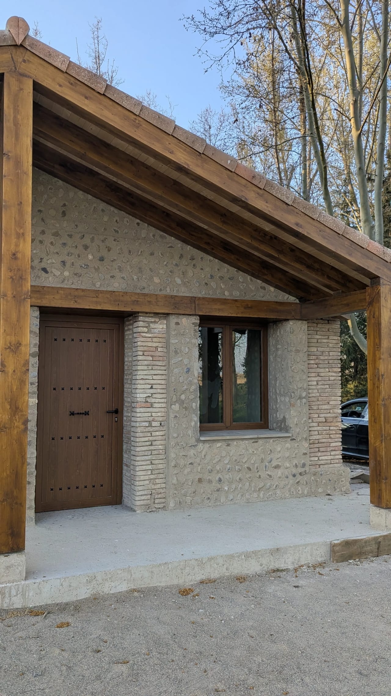 Casa rural con puerta y ventana de madera, construida con piedra y madera.