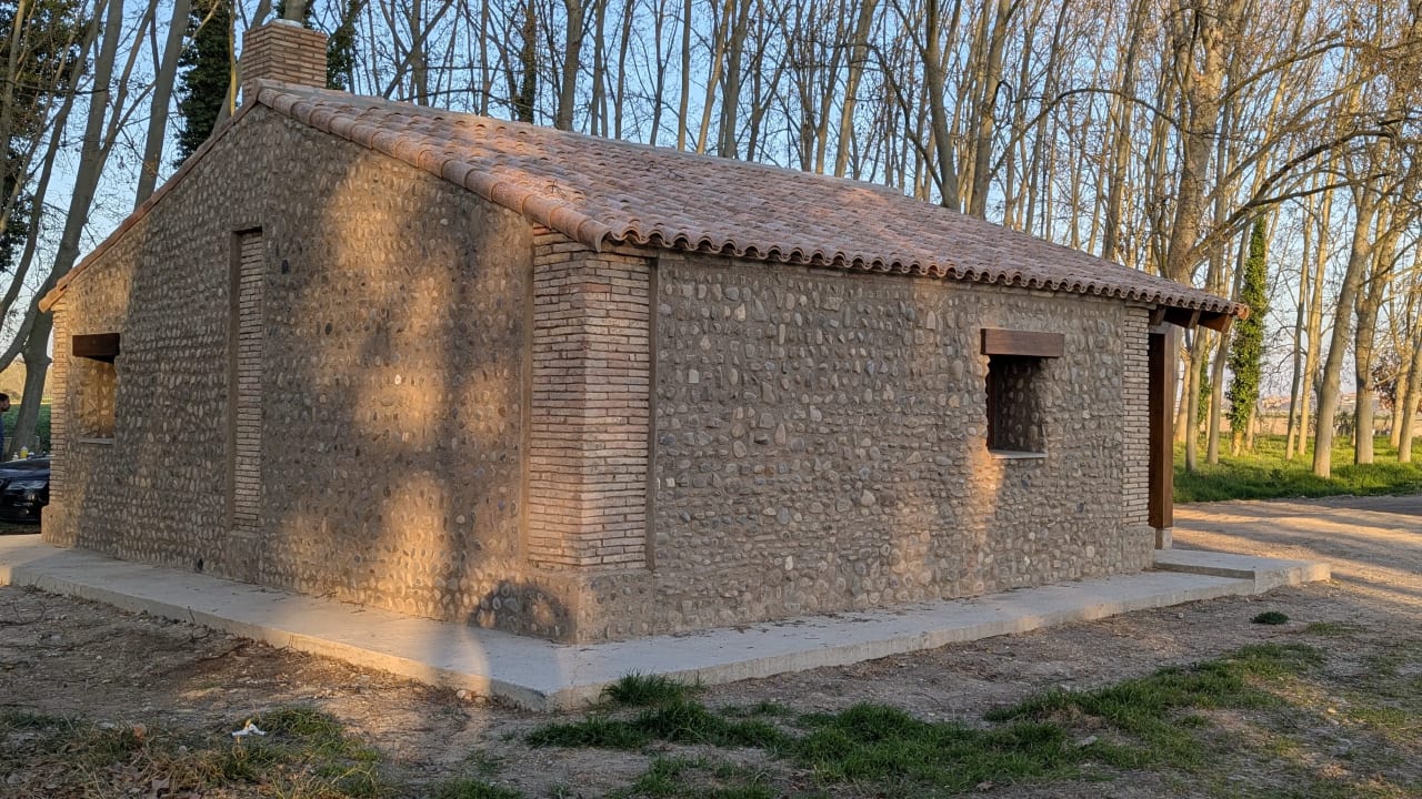 Casa de piedra con tejado de tejas rojas en un entorno natural.