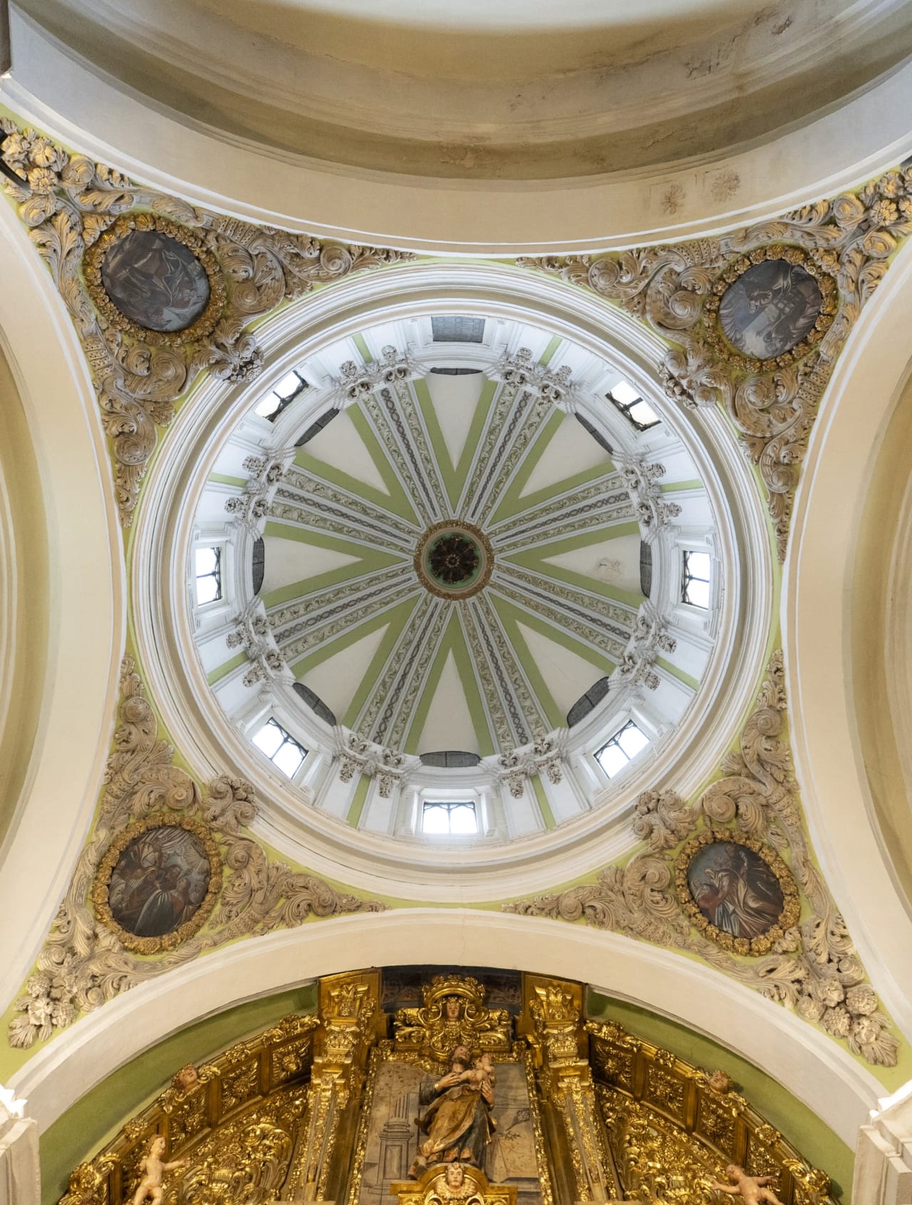 Cúpula decorada de una iglesia con detalles barrocos y religiosos.