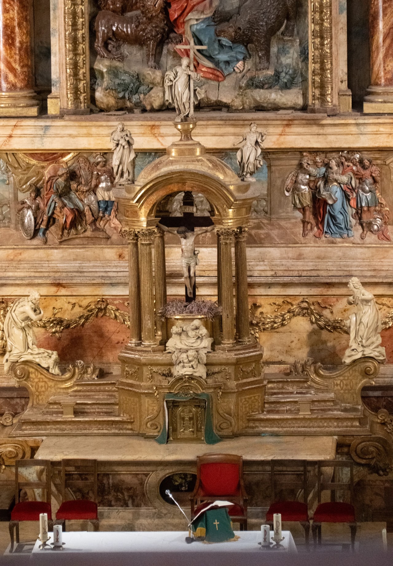 Altar de una iglesia con crucifijo y decoraciones doradas.