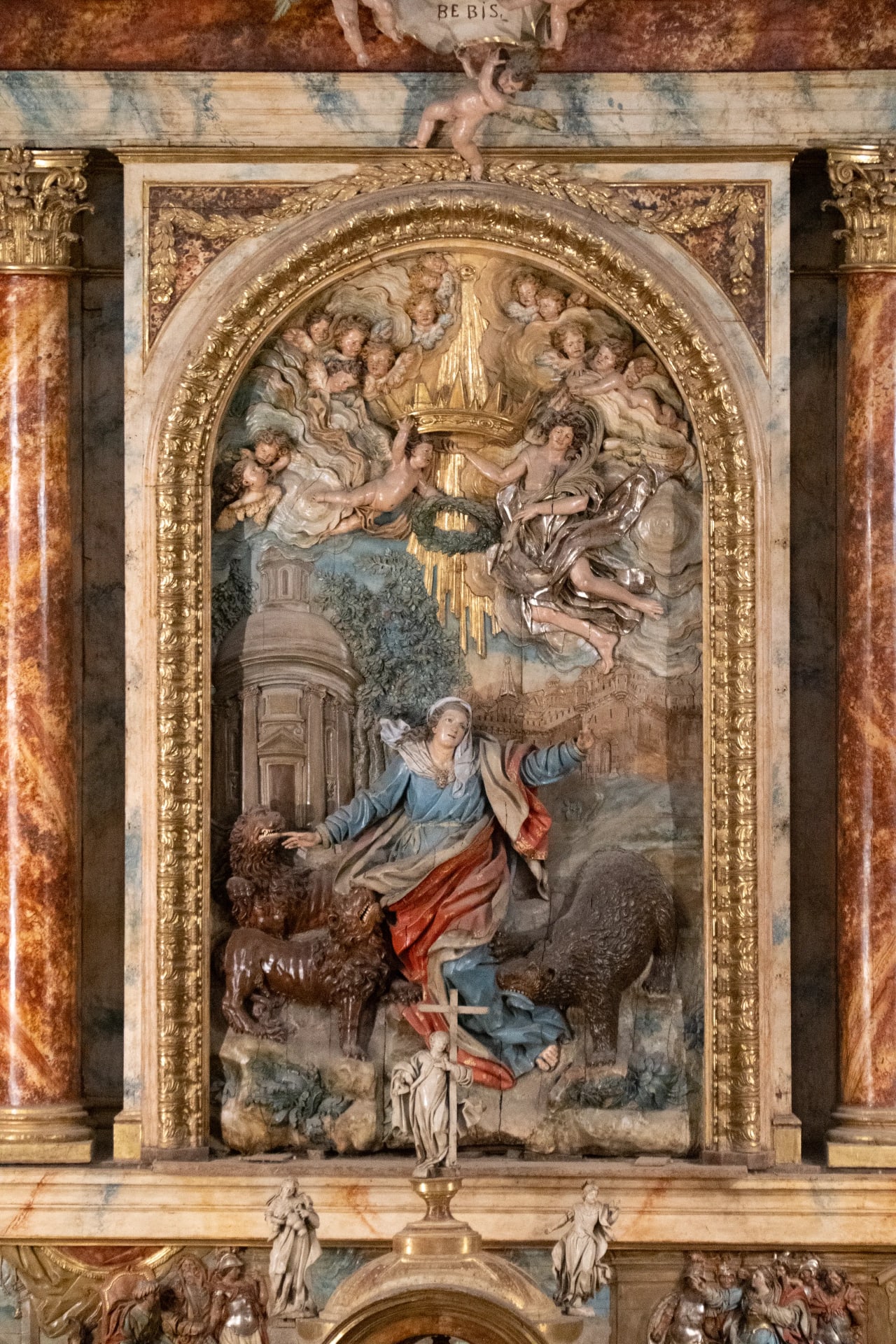 Escultura de Santa Catalina arrodillada con leones y ángeles.