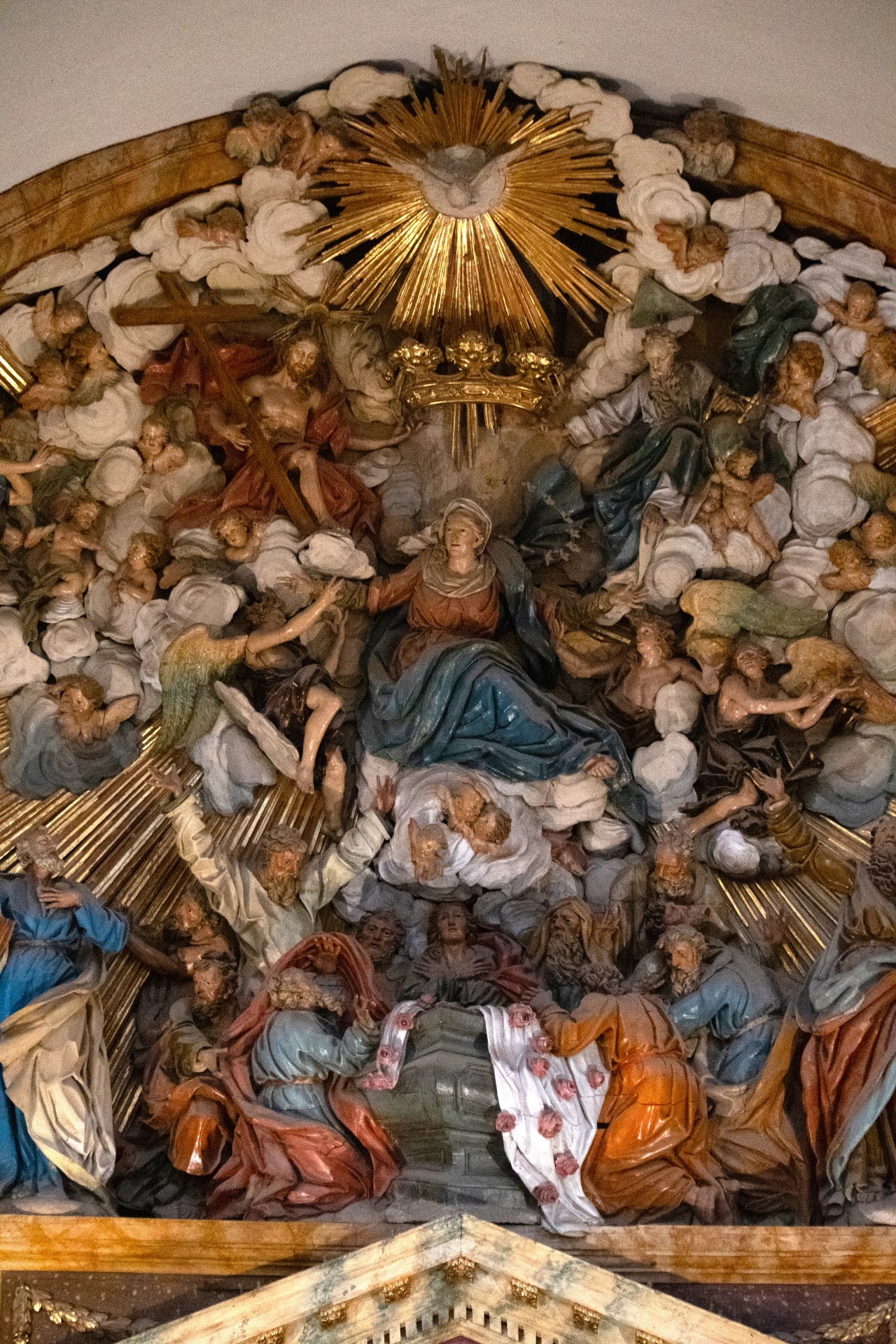 Escultura de la Asunción de la Virgen María, rodeada de ángeles y santos en una composición barroca.