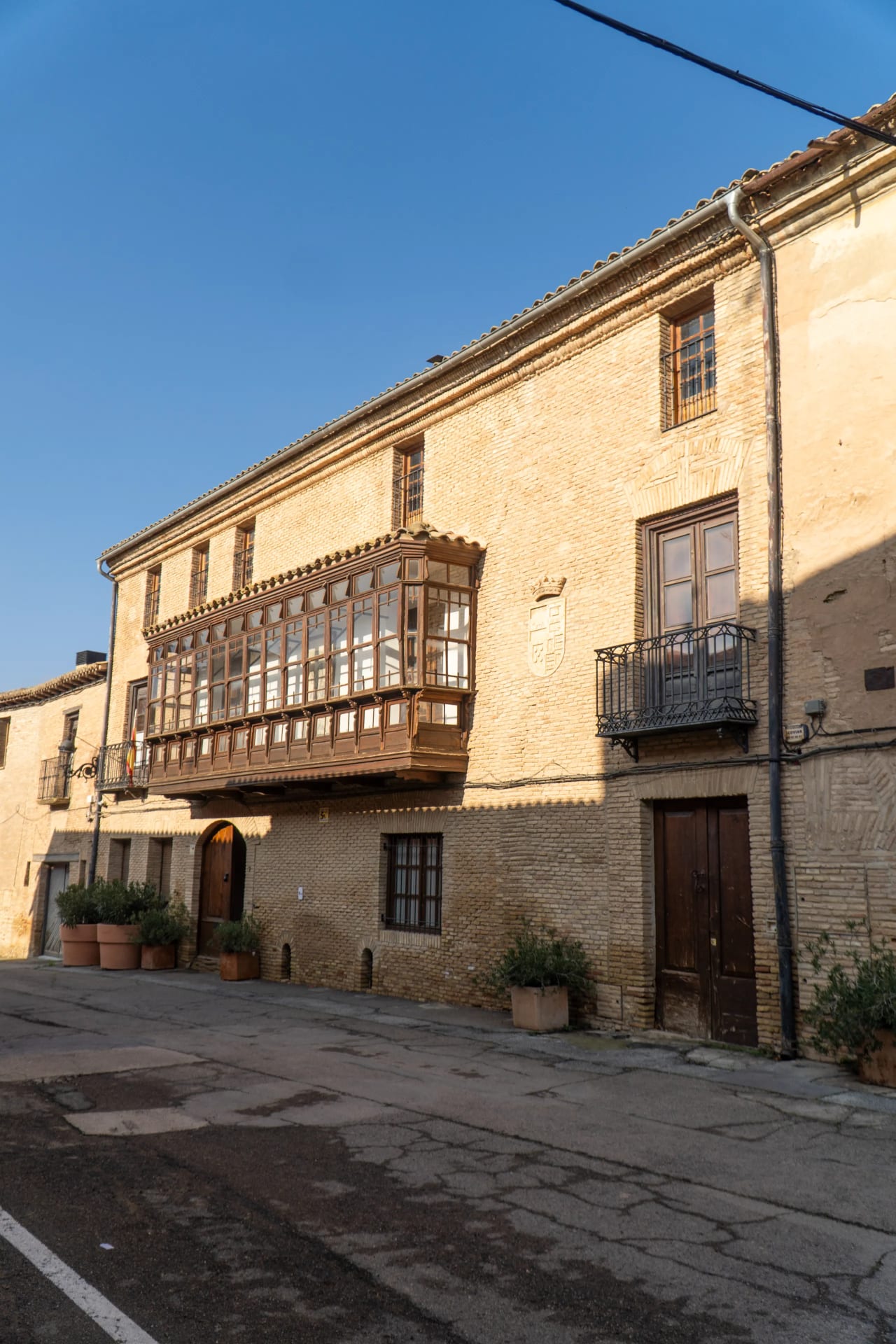 Casa antigua de ladrillo con balcón de madera y ventanas en fachada.
