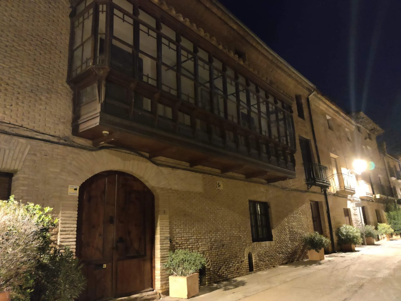 Edificio antiguo con balcón de madera y puerta principal.