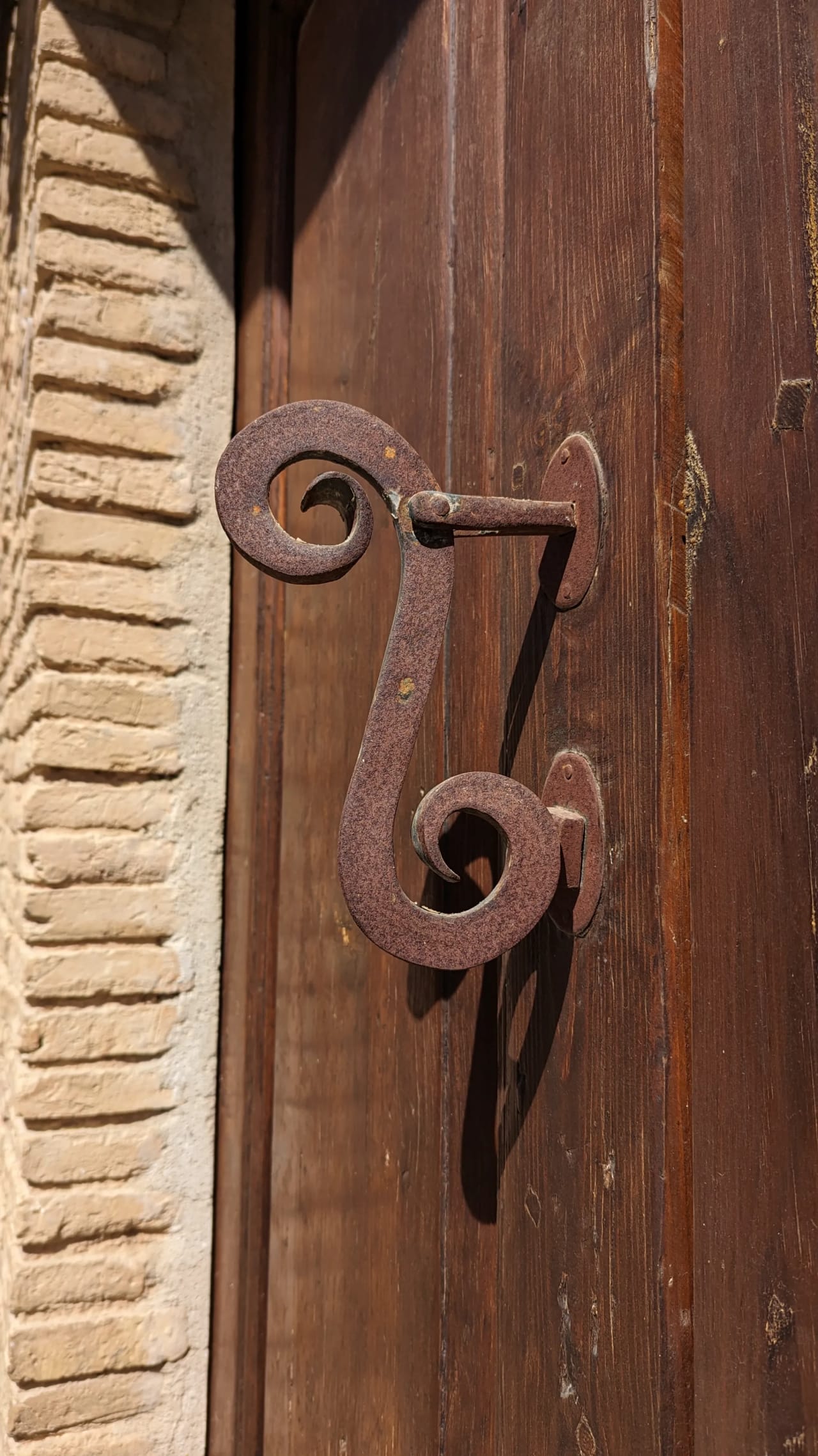 Perno de hierro oxidado en puerta de madera oscura.
