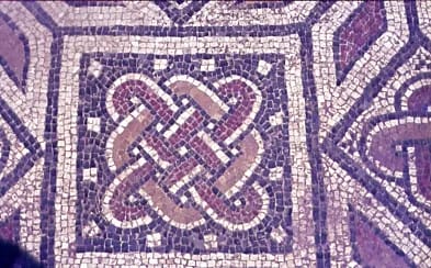 Mosaico de colores púrpura, blanco y marrón claro con diseño entrelazado.