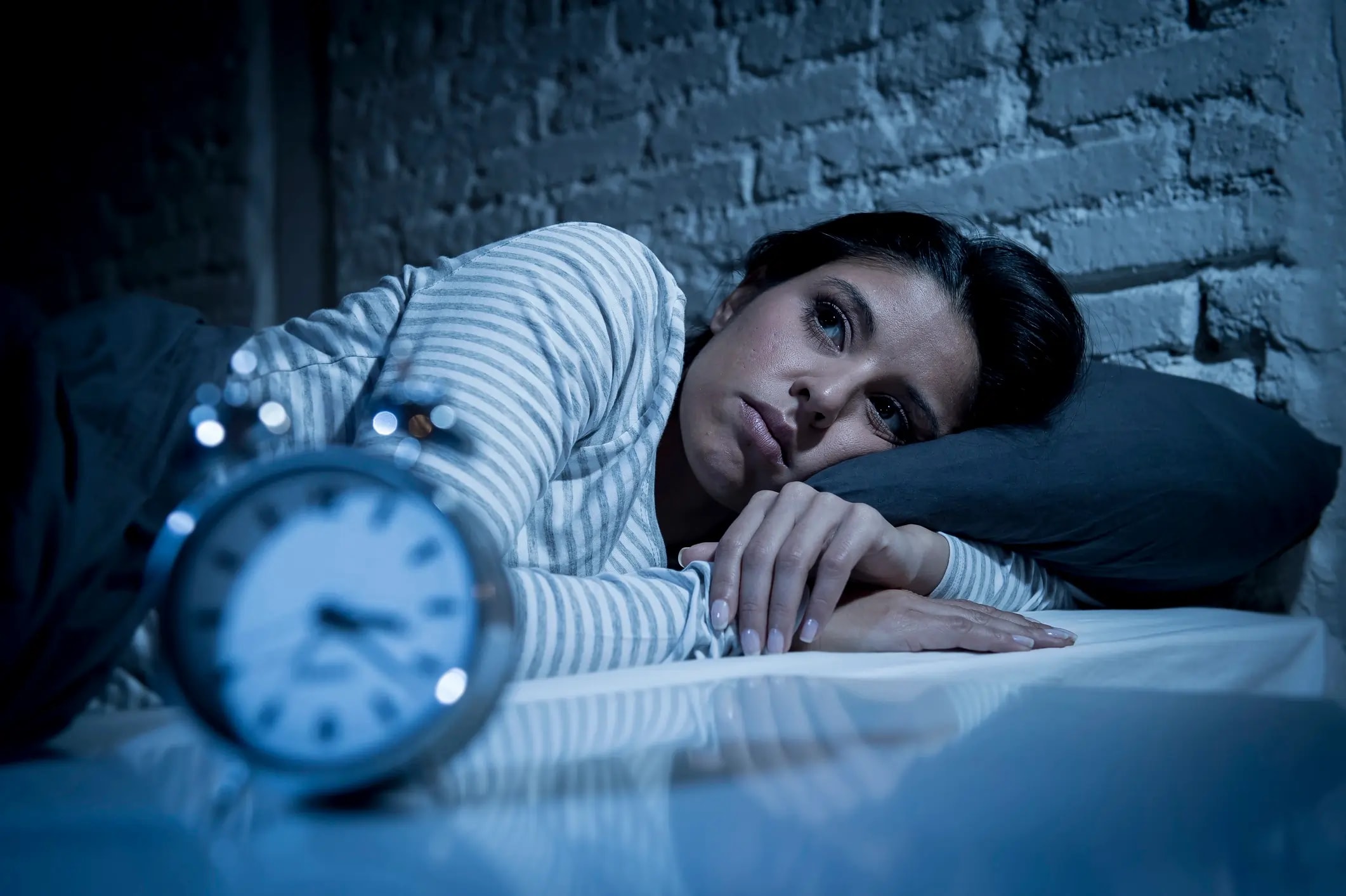Person awake in bed at night unable to sleep due to chronic sleep deprivation