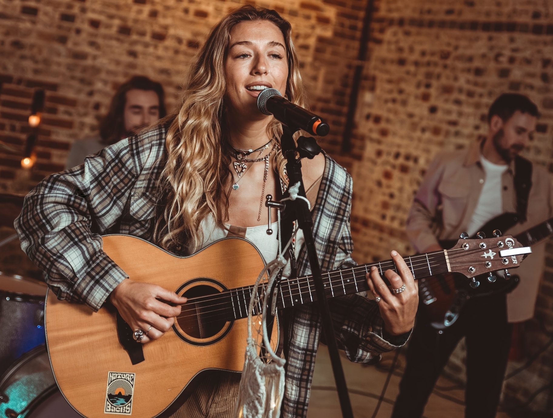 The Dreamers: Singer playing an acoustic guitar at a microphone, with bandmates behind her