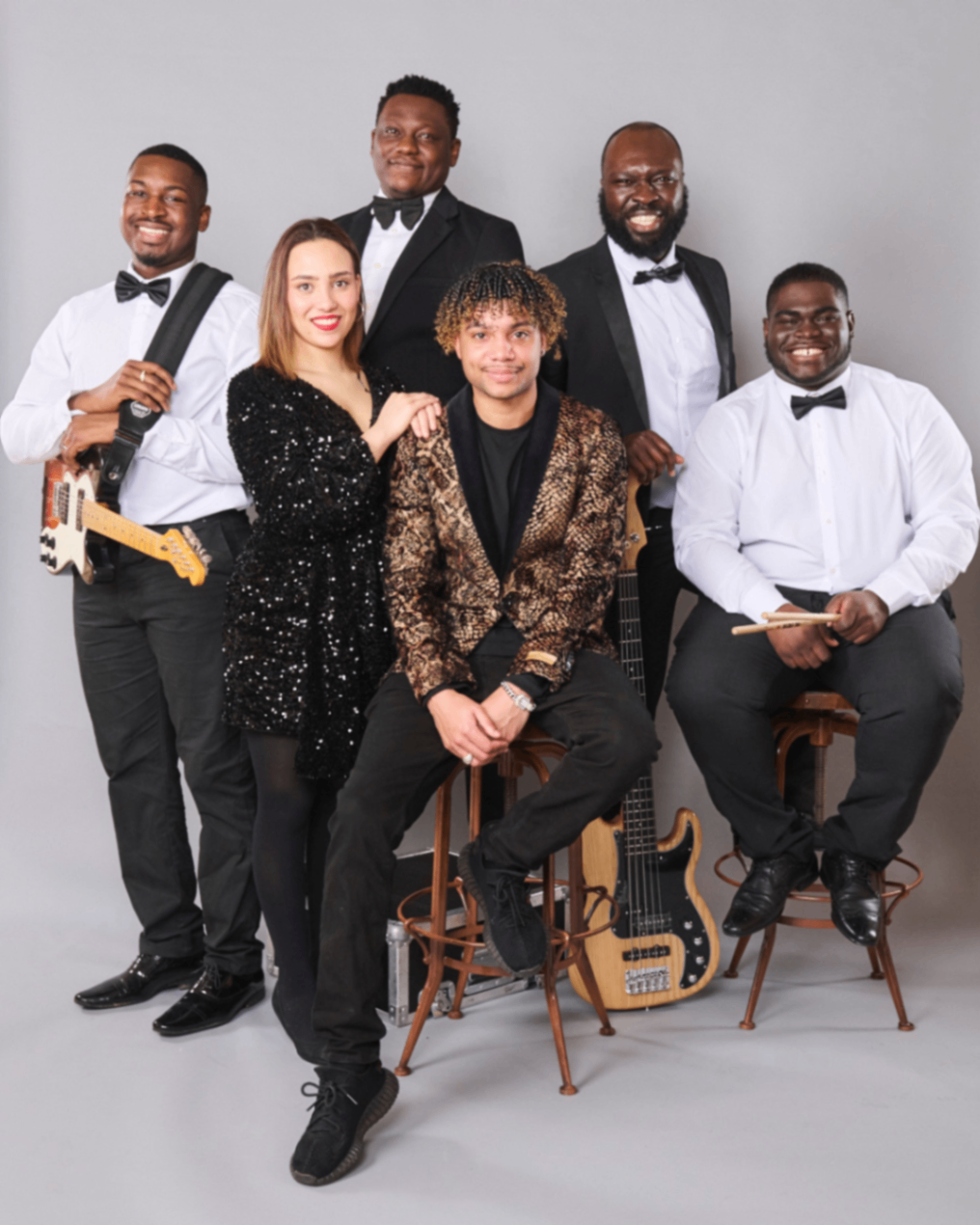 Afrodeziacz: Six band members posing in formalwear against a grey studio backdrop