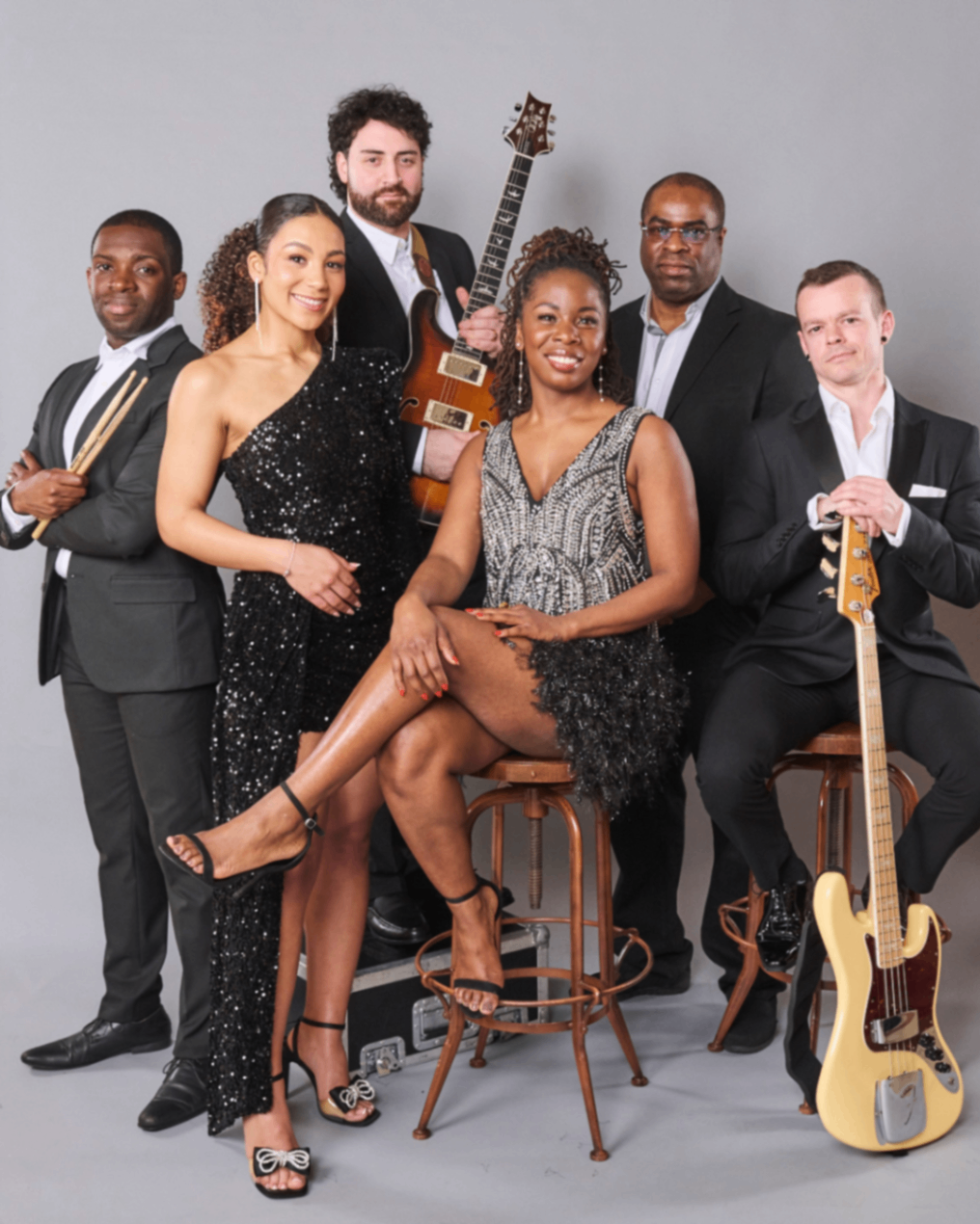 Motown Luxe: Six band members posing with instruments against a grey studio backdrop