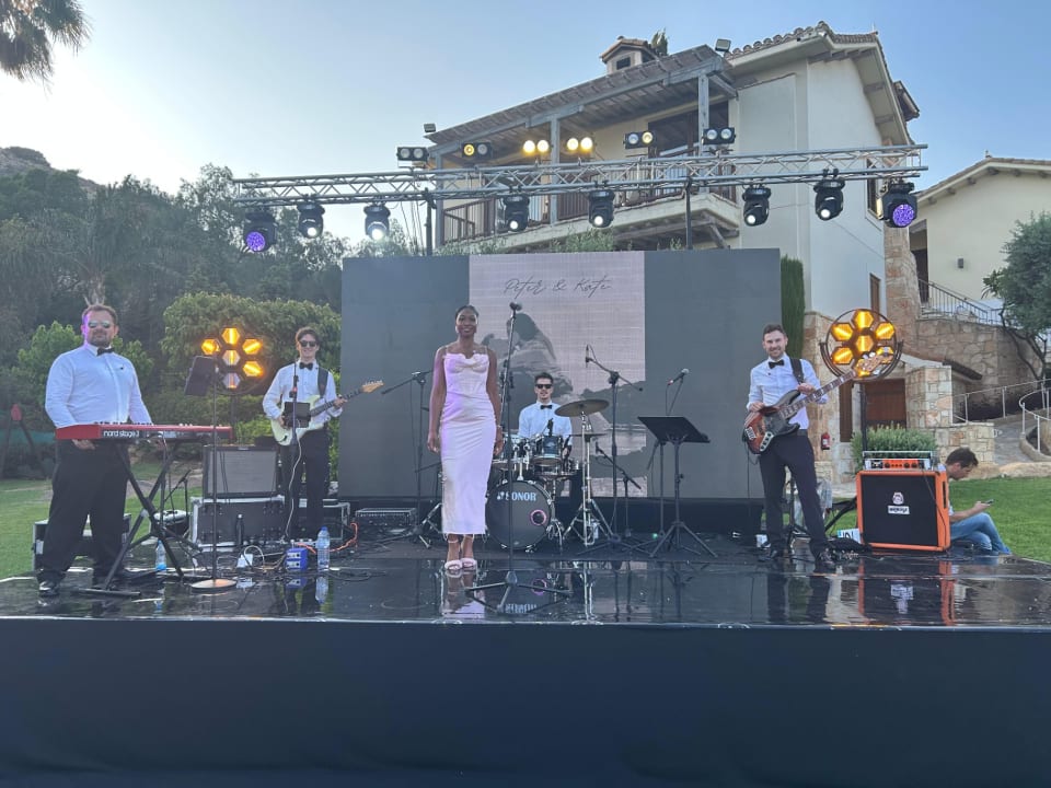 Dancefloor Magic: Five-piece band performing on an outdoor stage in front of a large building