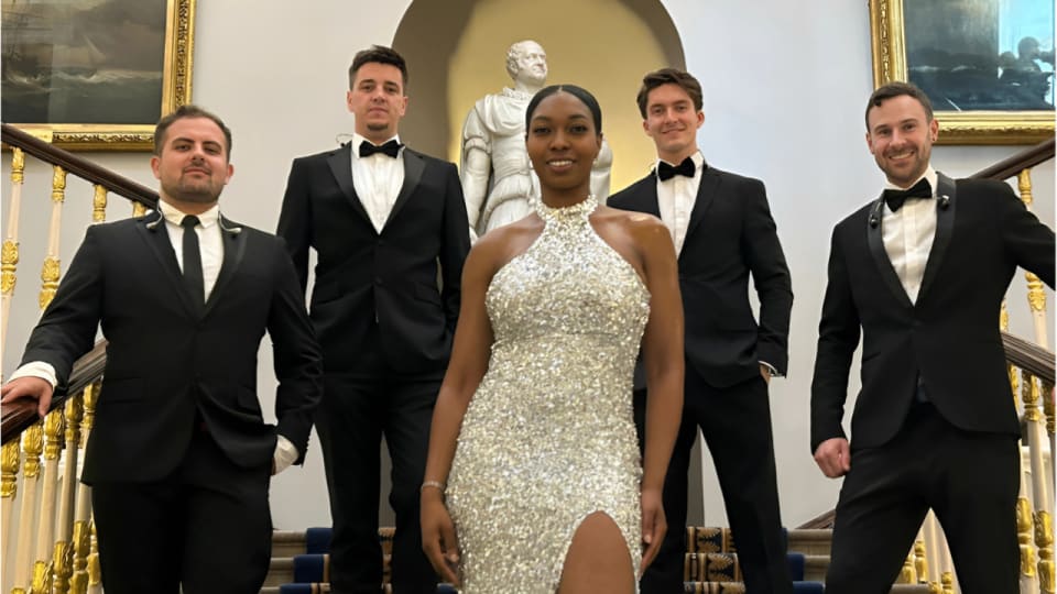 Dancefloor Magic: Five band members in formalwear posing on an ornate indoor staircase