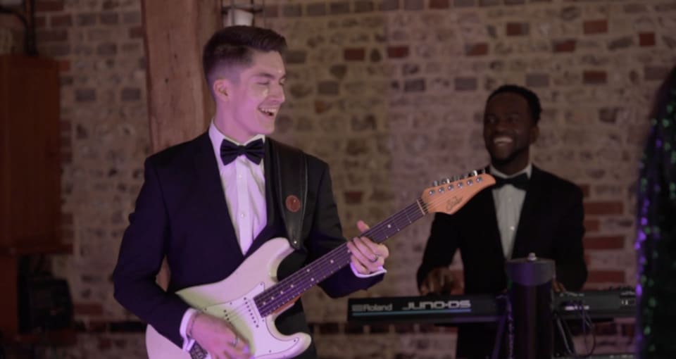 Dancefloor Magic: Guitarist in a tuxedo playing a white electric guitar with keyboardist behind him