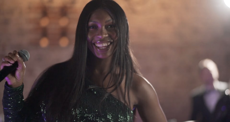 Dancefloor Magic: Smiling vocalist holding a microphone under warm stage lighting