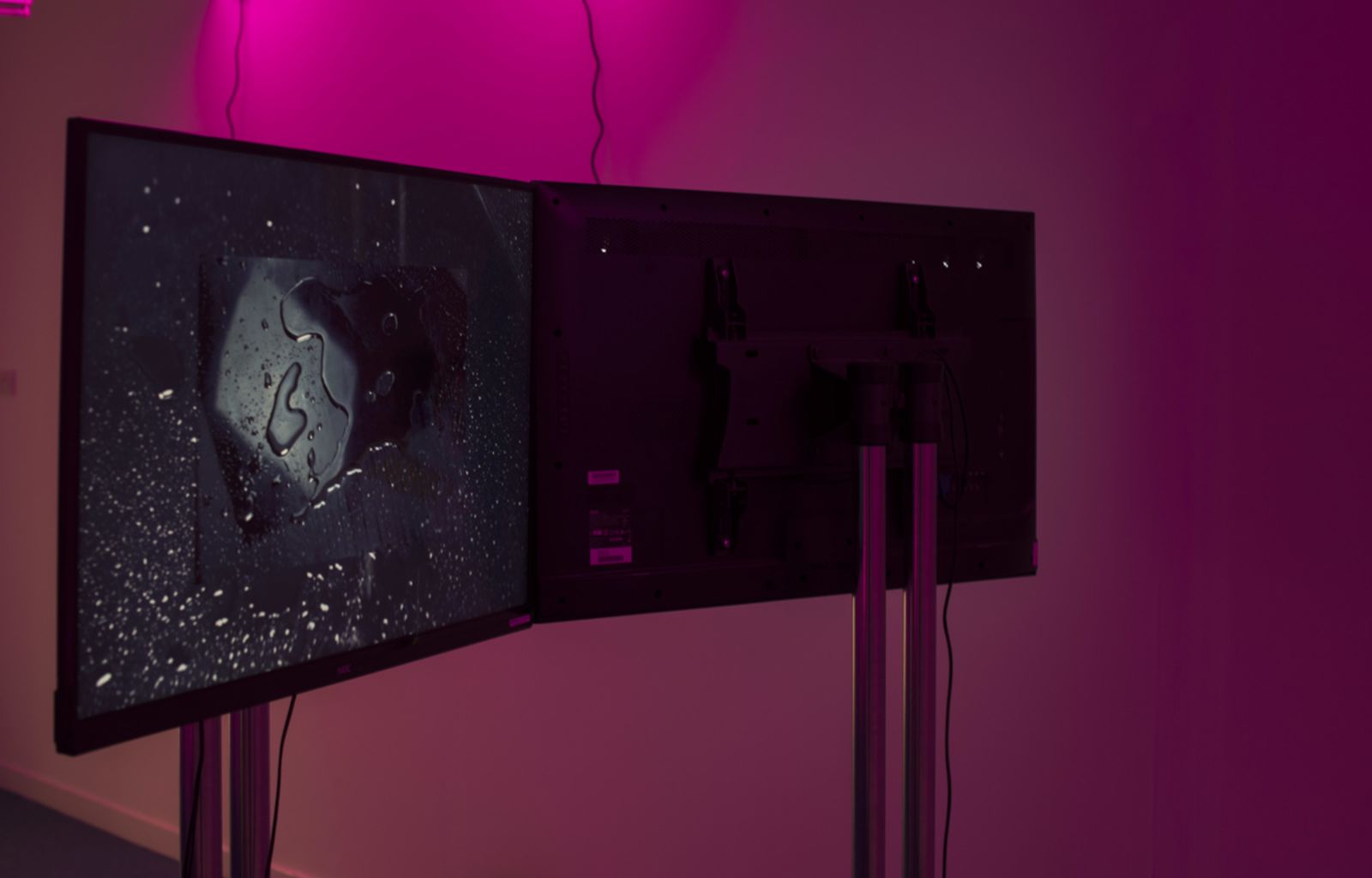 Pink hue fills the space with two TVs facing opposite direction show Lavendar Heated to 60c film.