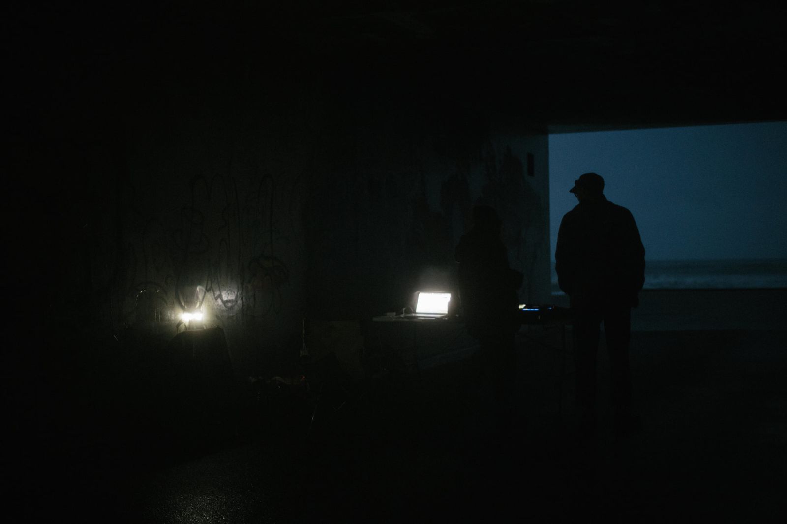 It's dark, its october in Aberdeen, maybe arond 8pm and light from a electric lantern and laptop fill the scene with dim light. Figures can just be made out standing inside a tunnels next to the beach.
