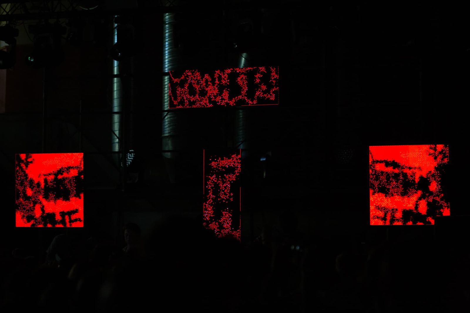 4 LED panels attatched to scaffolding in dark environment showing red distrorted graffiti