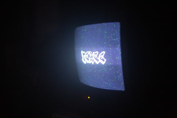 CRT TV shows text Peace in a grafitti front in the dark