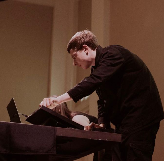 A man twists a knob on a electronic music instrument