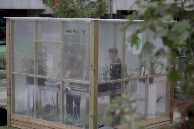 Two men DJ vinyl records inside semi-transprent greenhouse