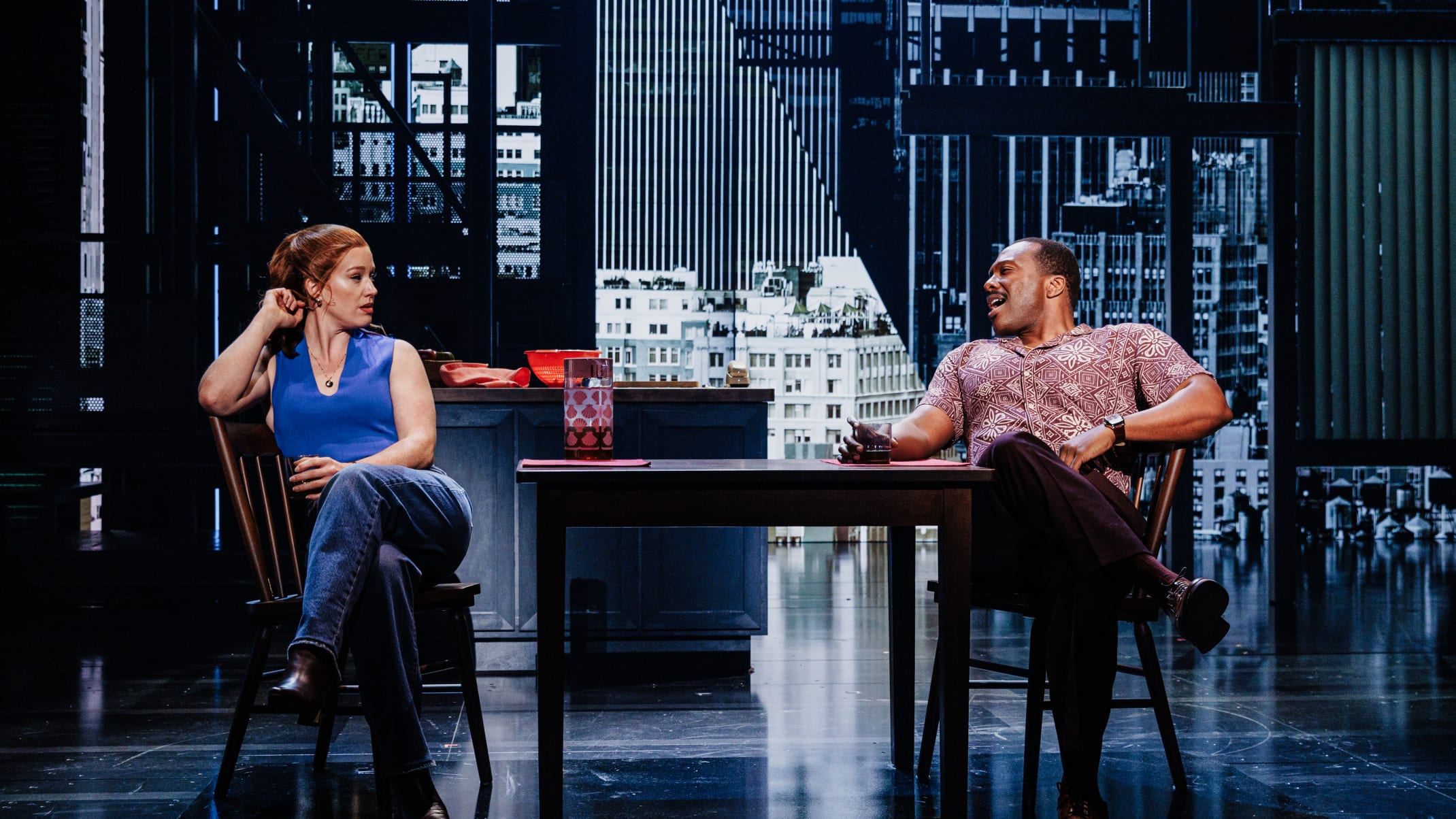 A woman and a man talking at a kitchen table.