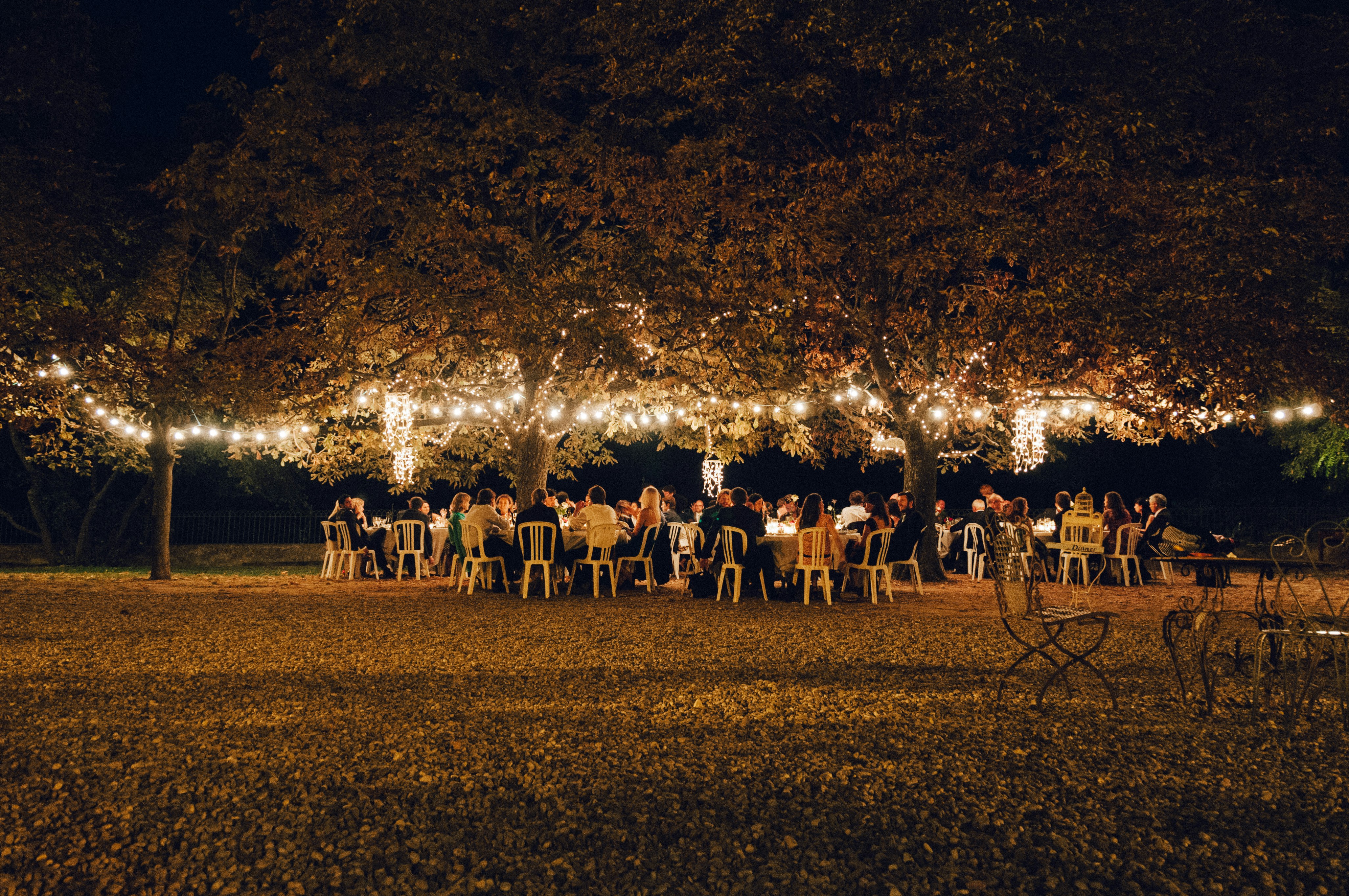 Outdoor event space at night with trees wrapped in warm lights for a party.