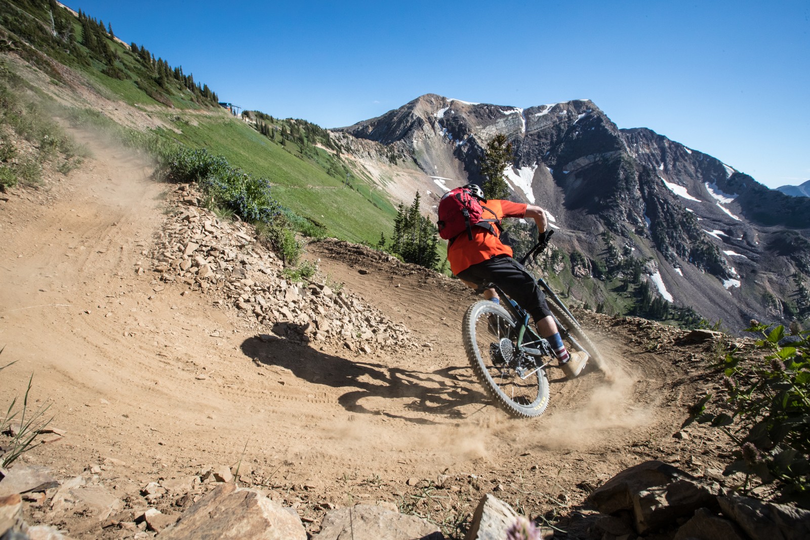 Mountain biker riding on a dirt trail with mountains in the background