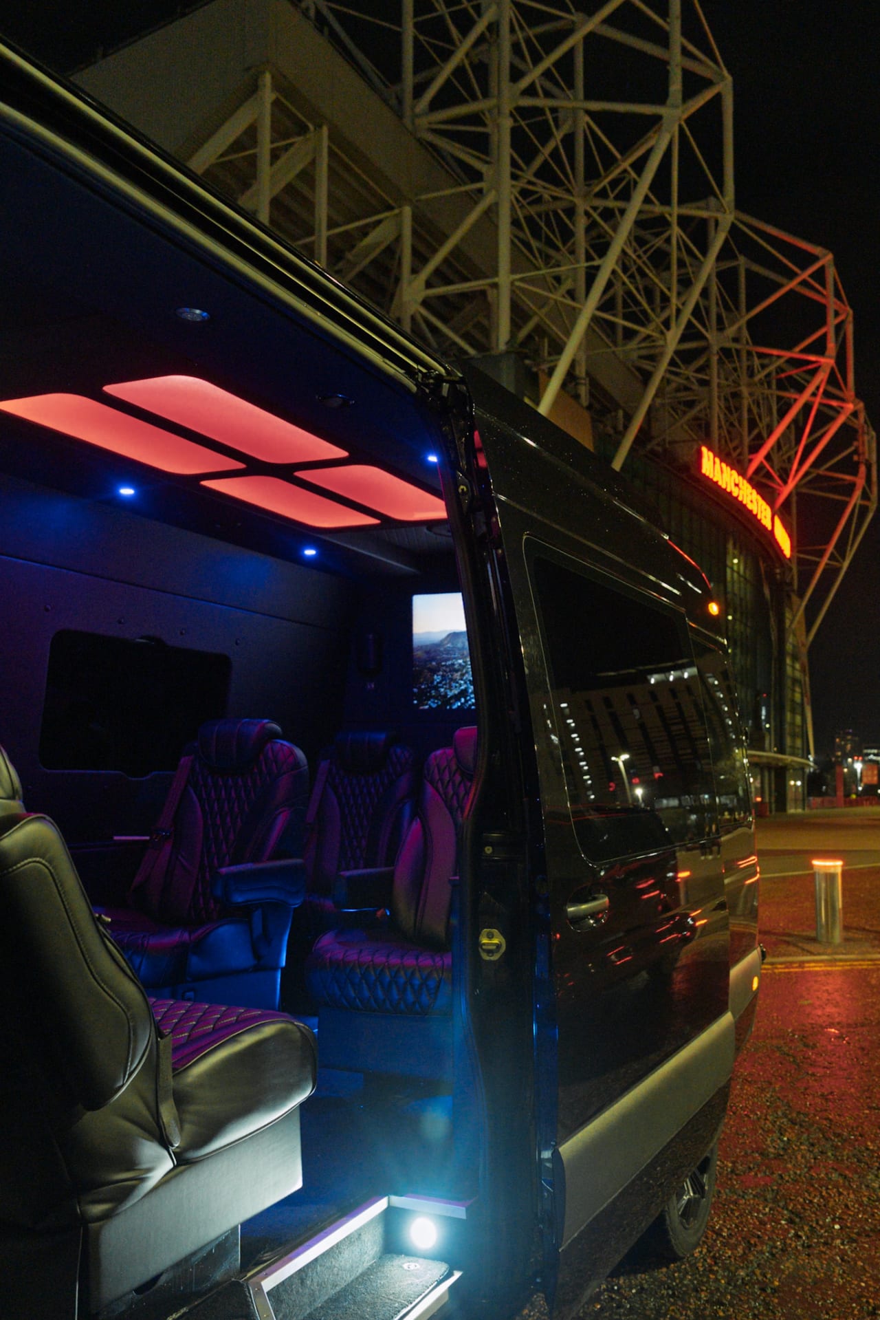 The Sprinter at night with the side door open and the cabin lit