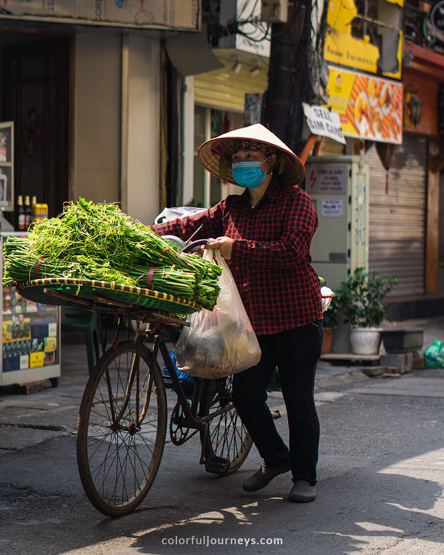 A woman sells fresh goods from her bicycle in Hanoi, Vietnam