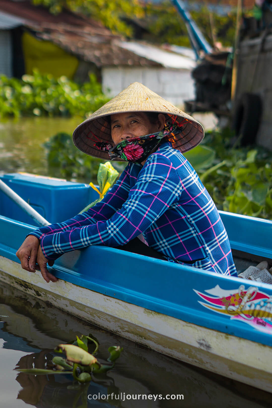 A woman wearing a non la sits in a blue boat.