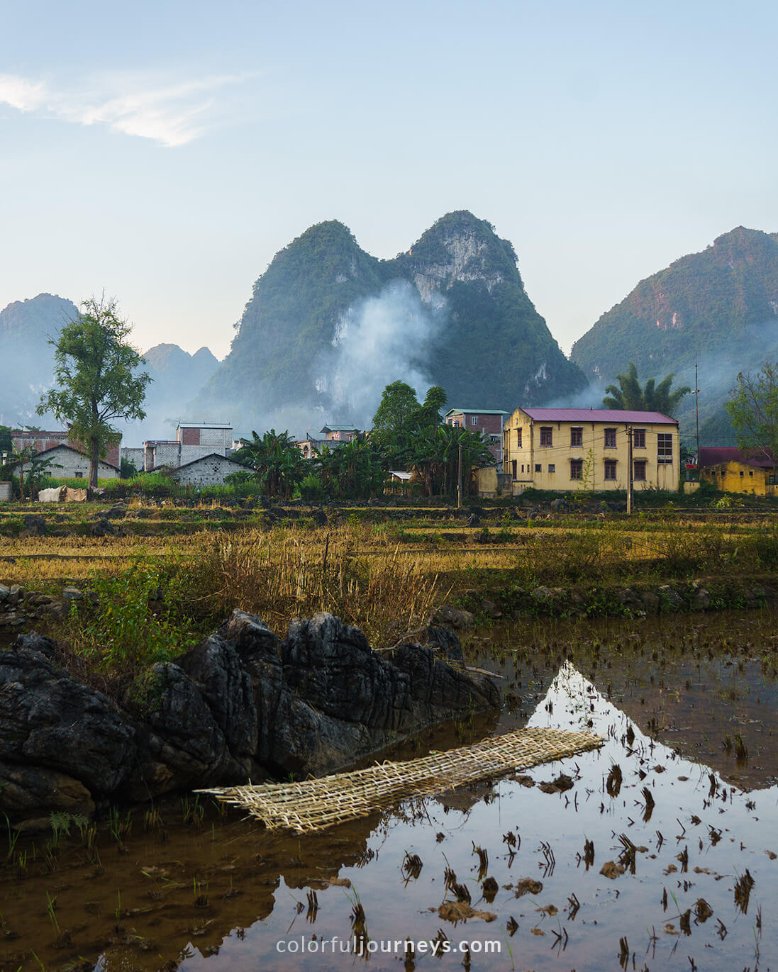 A house with mountains in the background and water in the foreground