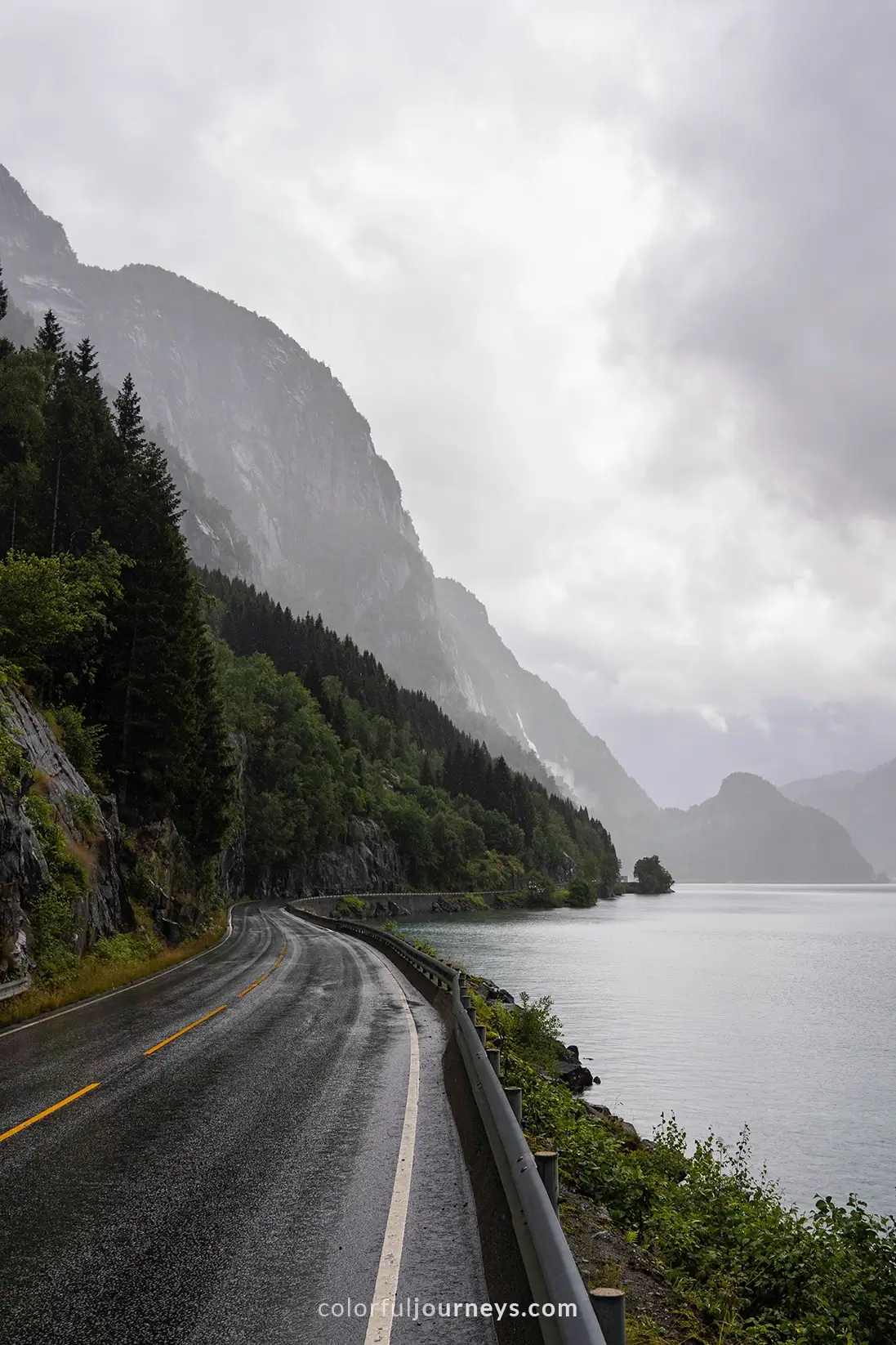 A road passes dramatic cliffs and a fjord in Norway