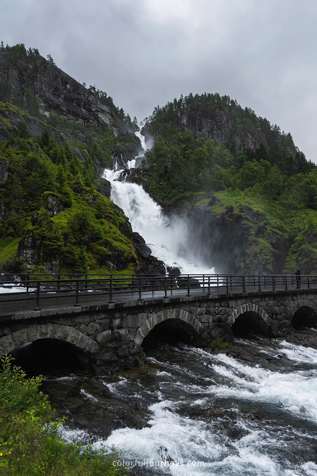 A waterfall flows under a bridge in Norway