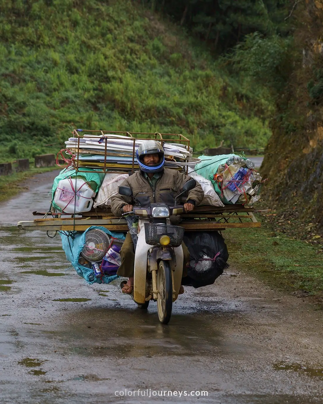 A man rides a motorbike packed with things