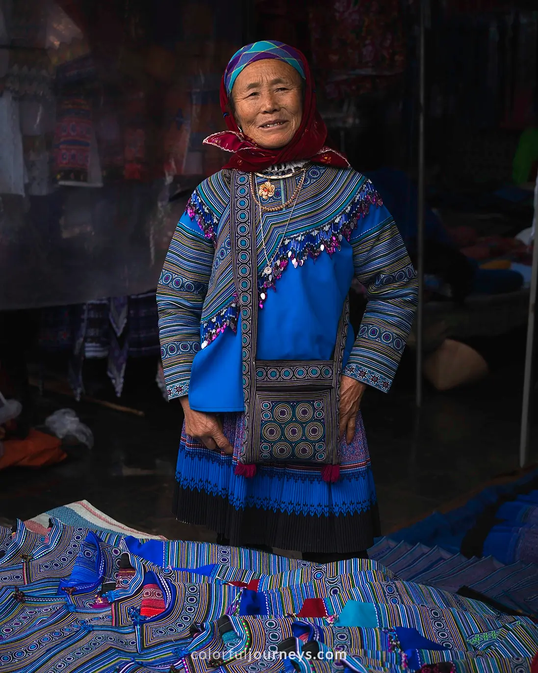 A woman dressed in colorful traditional clothes sells clothes